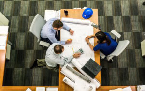 three diverse professionals working on a project around a table