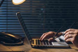 man at laptop with glasses next to phone