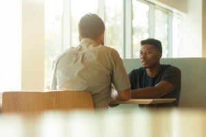 two professionals at table discussing leadership mistakes