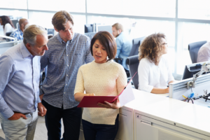 female leader discussing project in folder to older male colleagues