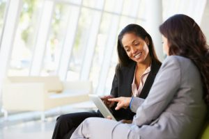 Two female customer success consultants working together to align their sales and marketing teams. 